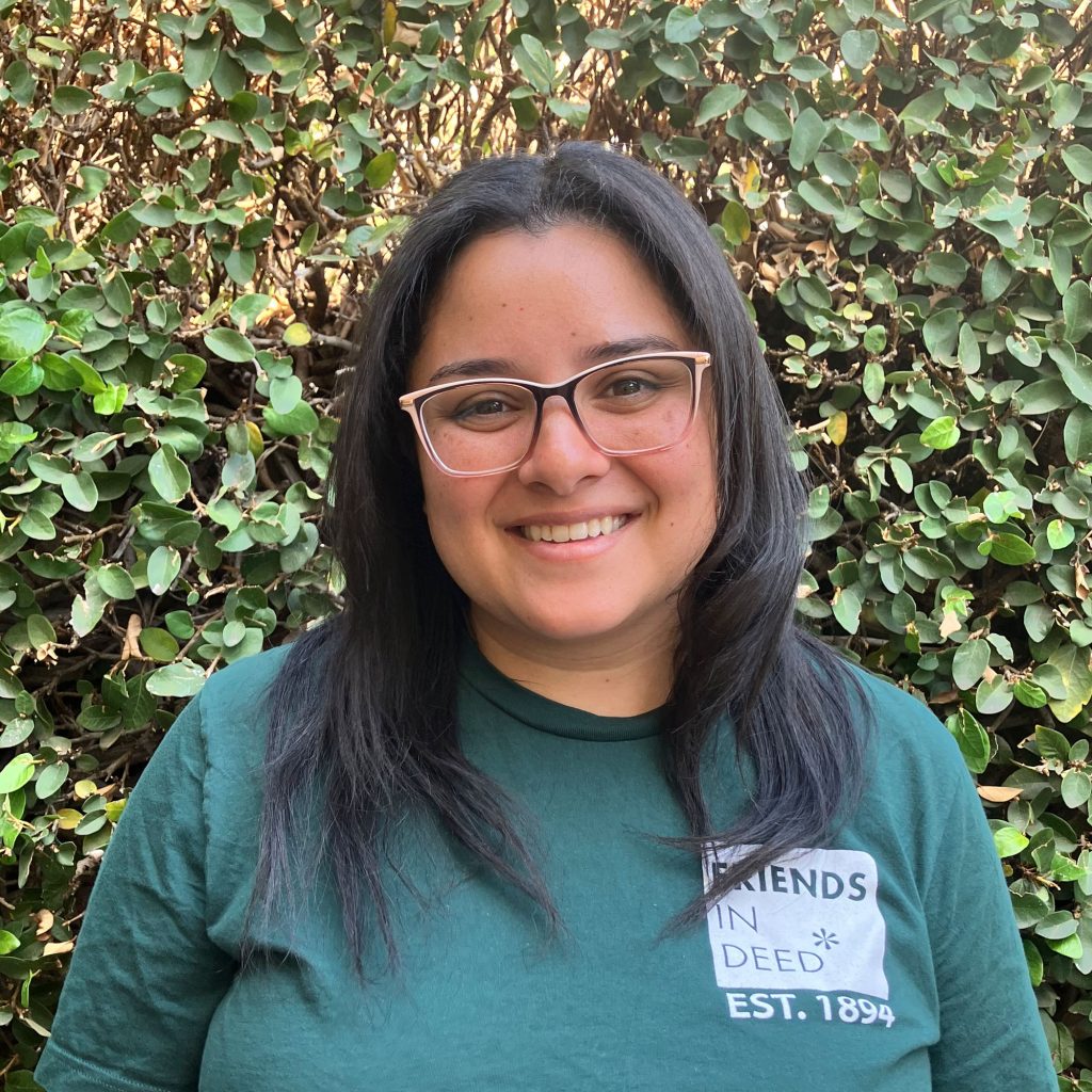 Portrait of Amanda Estrada Paez standing in front of greenery.